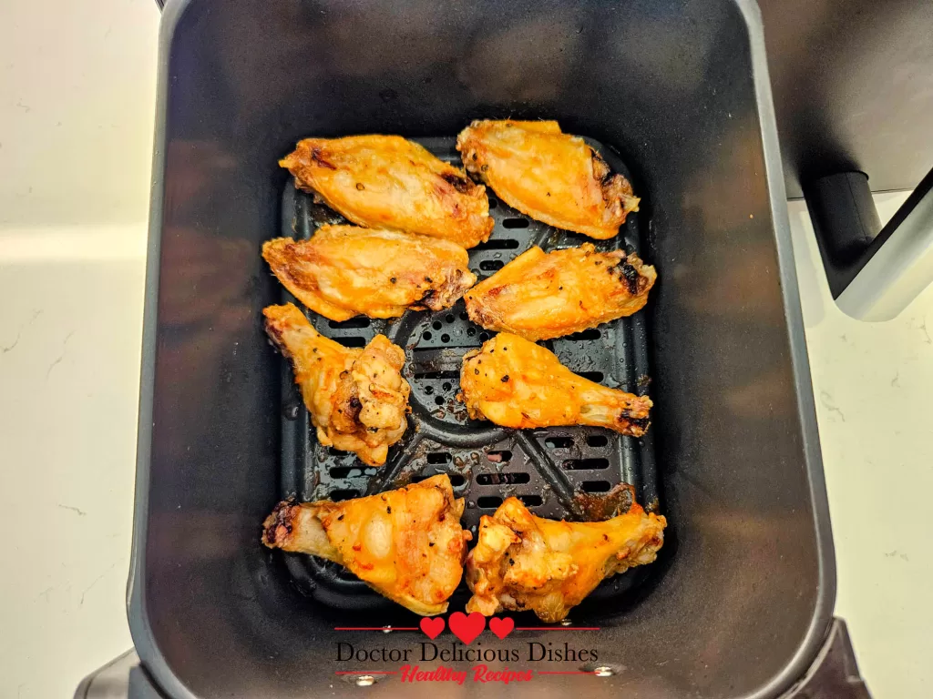 Crispy and golden chicken wings fully cooked inside air fryer basket.