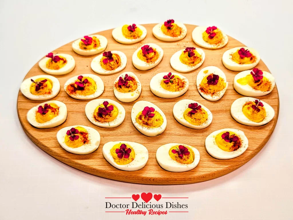 Deviled Eggs Recipe – finished platter of deviled eggs garnished with paprika and herbs on wooden board