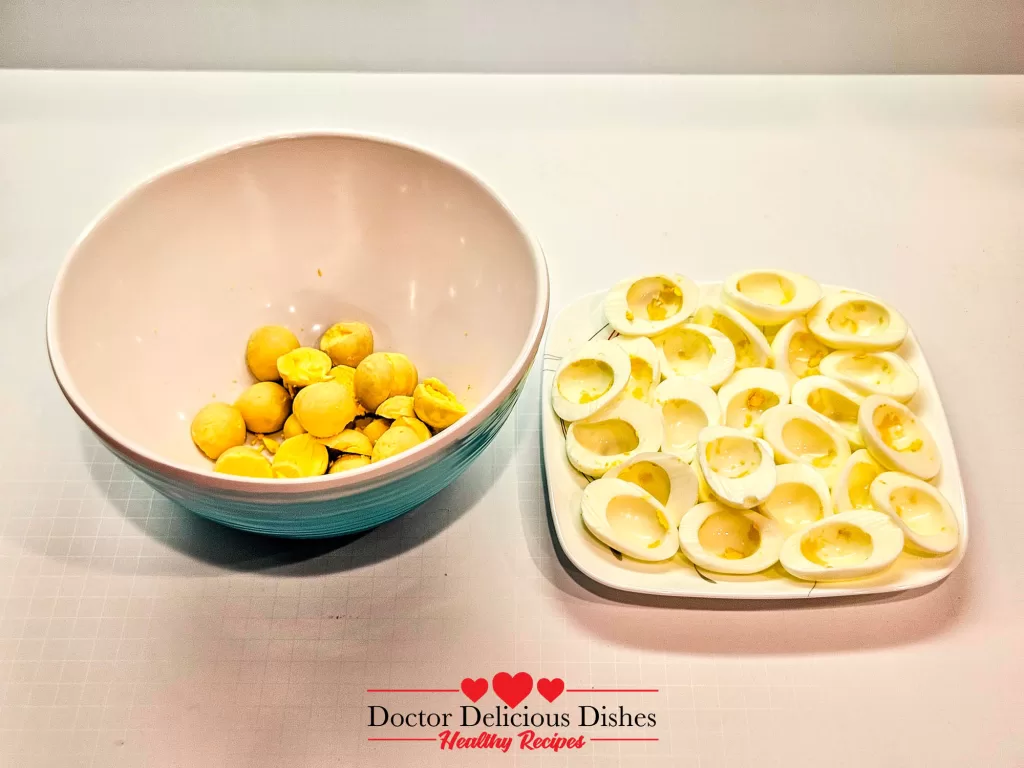 Deviled Eggs Recipe – boiled egg yolks separated in bowl with empty whites on a plate