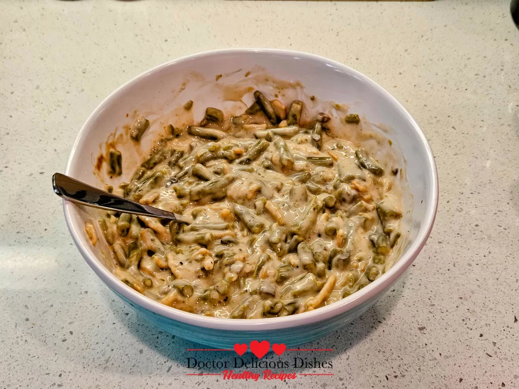 Mixing green beans with cream of mushroom soup to prepare green bean casserole recipe filling