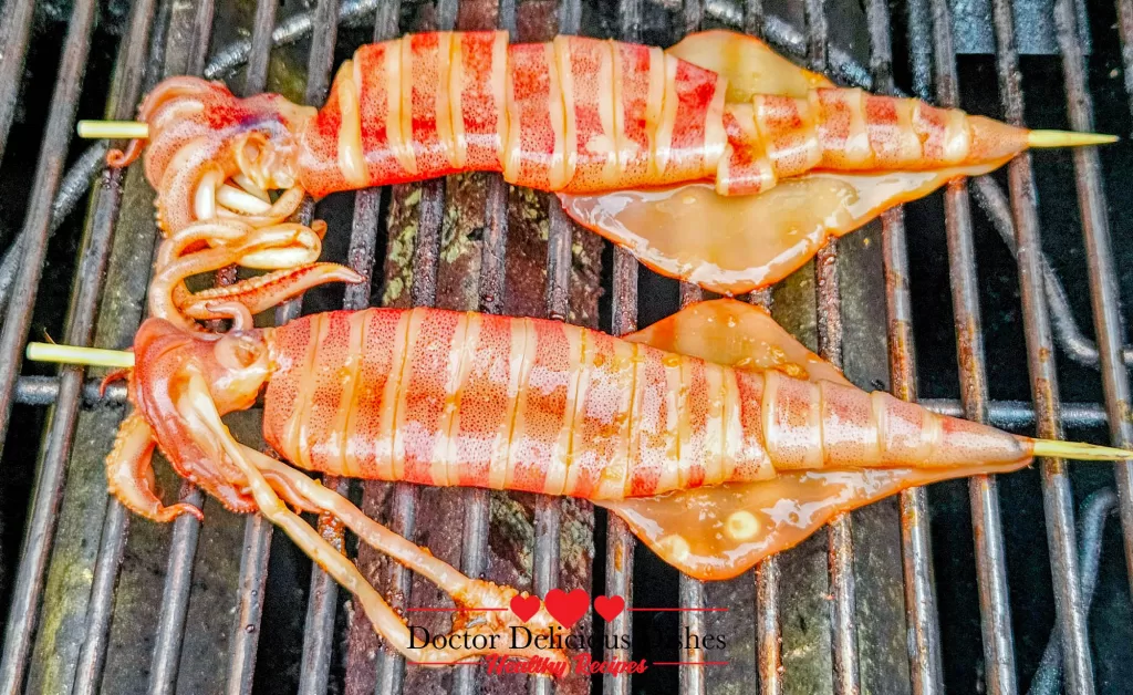 Freshly marinated squid skewers placed on the grill to make Japanese grilled squid (Ikayaki).