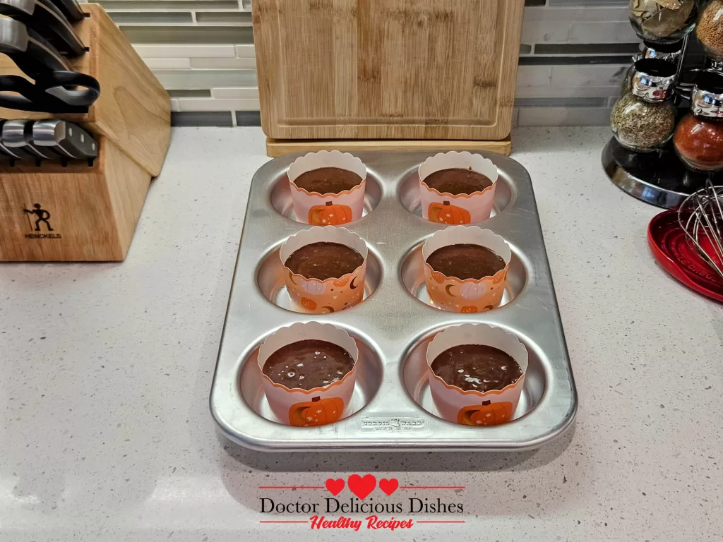 Chocolate cupcake batter poured into pumpkin liners for Halloween cupcakes.