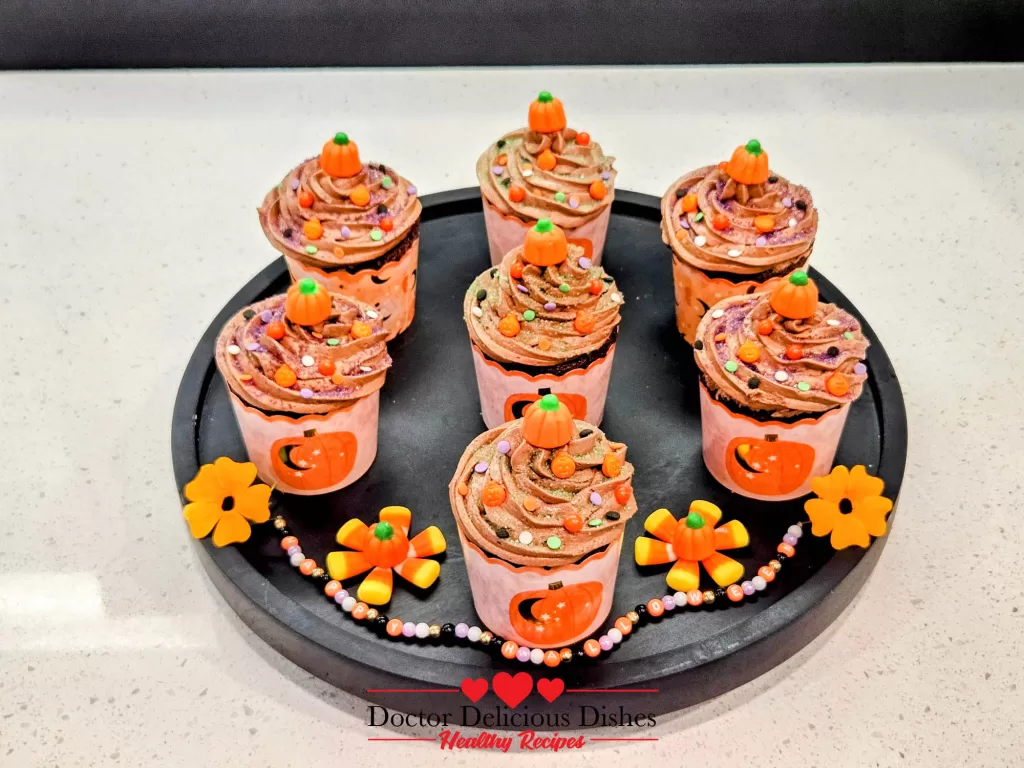 Finished Halloween cupcakes decorated with protein frosting, sprinkles, and pumpkin toppers.