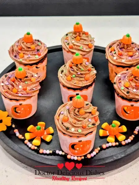 Finished Halloween cupcakes decorated with protein frosting, sprinkles, and pumpkin toppers.