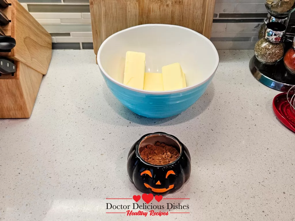 Butter and cocoa powder in a bowl as frosting base for Halloween cupcakes.
