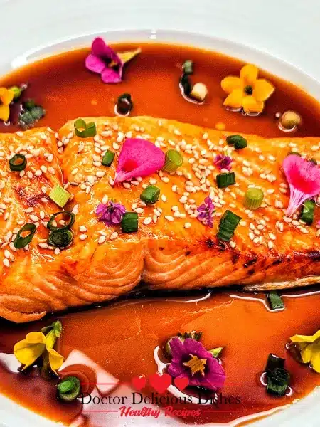 Teriyaki Salmon garnished with sesame seeds and scallions in sauce.