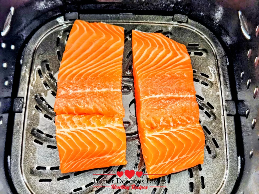Salmon fillets skin-side down in the air fryer basket for Air Fryer Salmon.