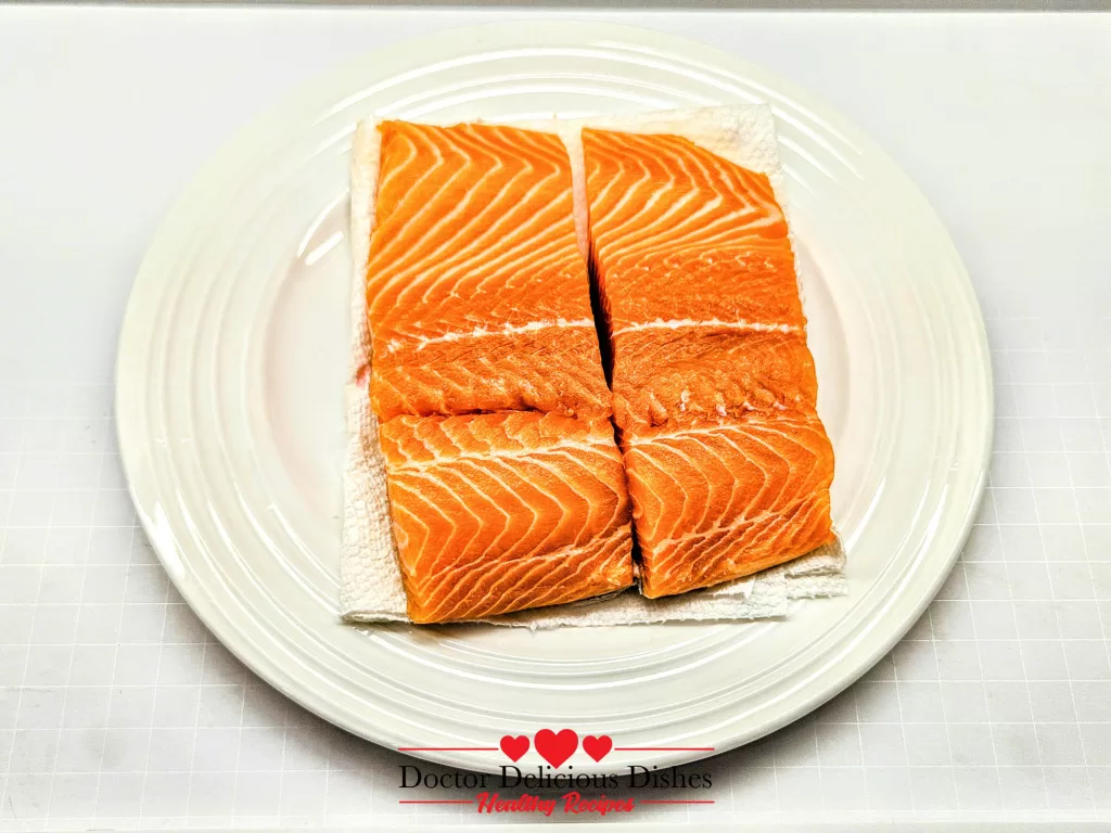 Salmon fillets resting on paper towels before air frying.