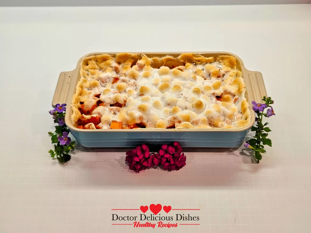 Finished sweet potato casserole recipe with toasted marshmallows styled with flowers.