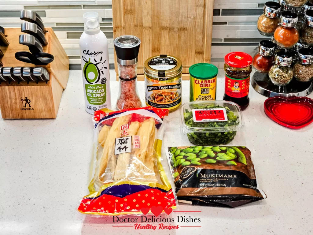 Ingredients for tofu skin recipe including dried tofu skin, preserved mustard greens, edamame, and seasonings arranged on kitchen counter.