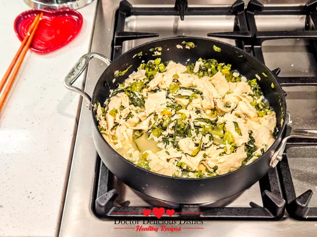 Tofu skin and mustard greens simmering together in pan for tofu skin recipe.