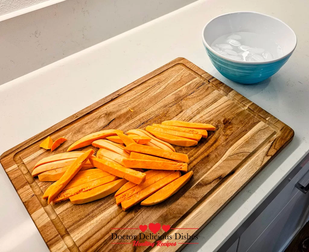 Raw sweet potato fries cut evenly on a wooden board before air frying – Doctor Delicious Dishes