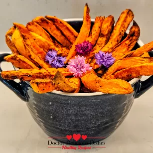 Golden crispy air fryer sweet potato fries styled in a blue bowl with edible flowers – Doctor Delicious Dishes