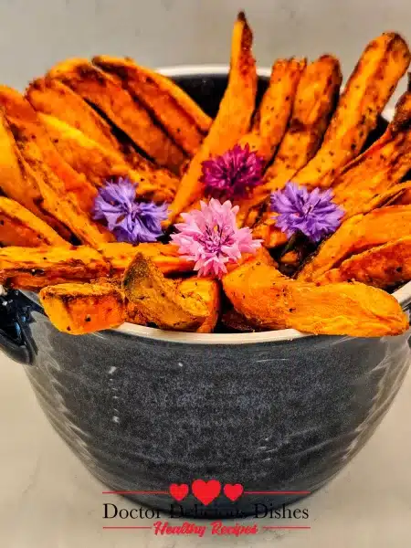 Golden crispy air fryer sweet potato fries styled in a blue bowl with edible flowers – Doctor Delicious Dishes