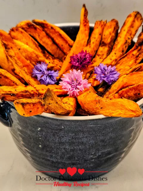 Golden crispy air fryer sweet potato fries styled in a blue bowl with edible flowers – Doctor Delicious Dishes
