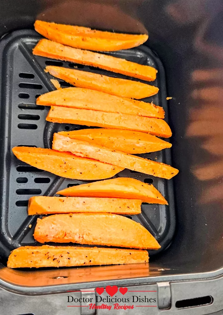 Raw seasoned sweet potato fries arranged in air fryer basket – Doctor Delicious Dishes