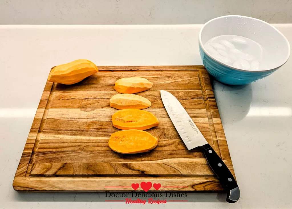 Sweet potatoes halved and peeled next to a bowl of ice water – prepping for air fryer sweet potato fries by Doctor Delicious Dishes