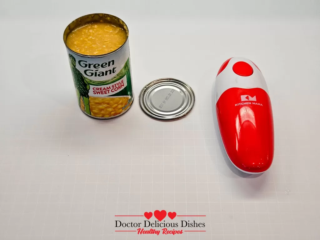 Can of cream-style corn opened with red Kitchen Mama can opener for Easy Corn Casserole Recipe.