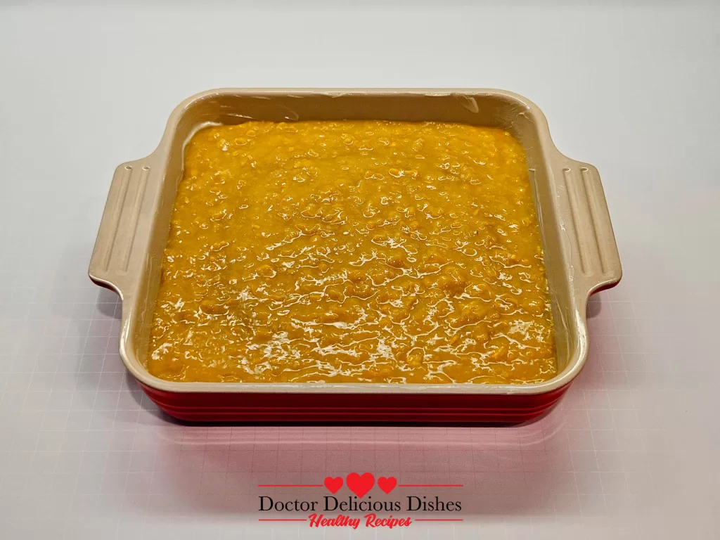 Cream-style sweet corn base prepared in a red casserole dish for Easy Corn Casserole Recipe.