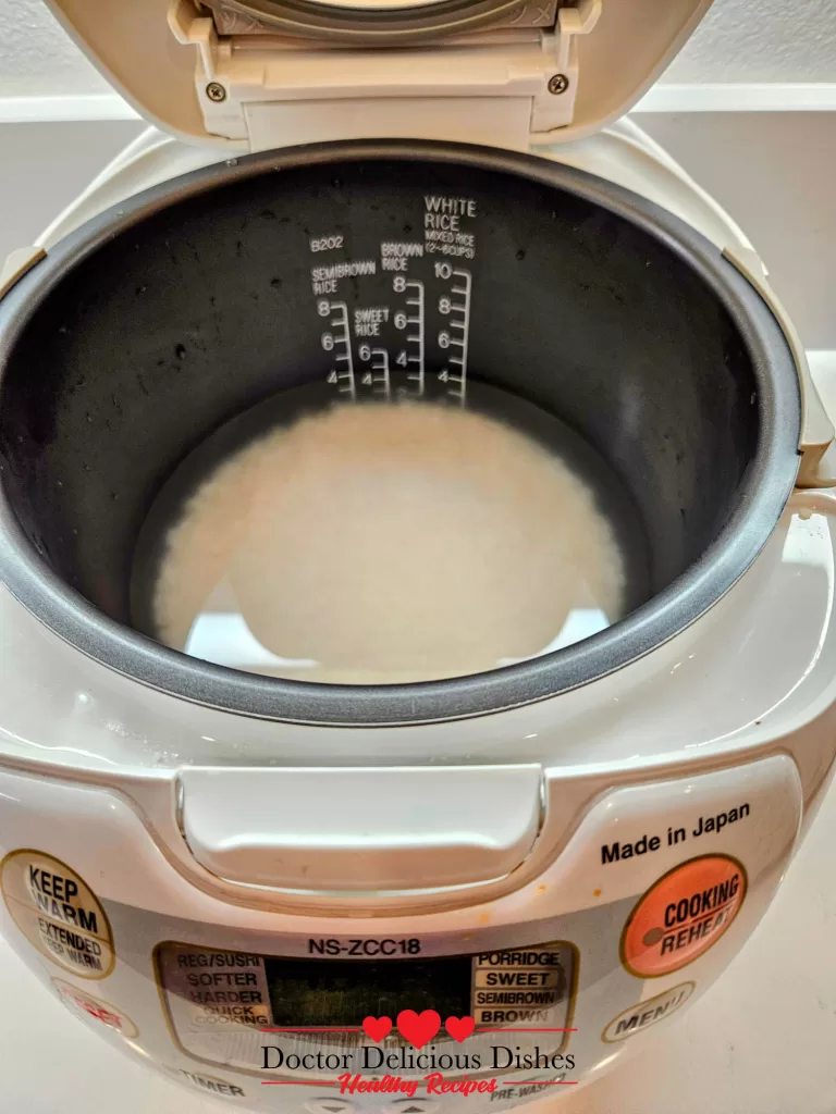 White rice soaking in a Japanese rice cooker for Chicken Soboro Don by Doctor Delicious Dishes.