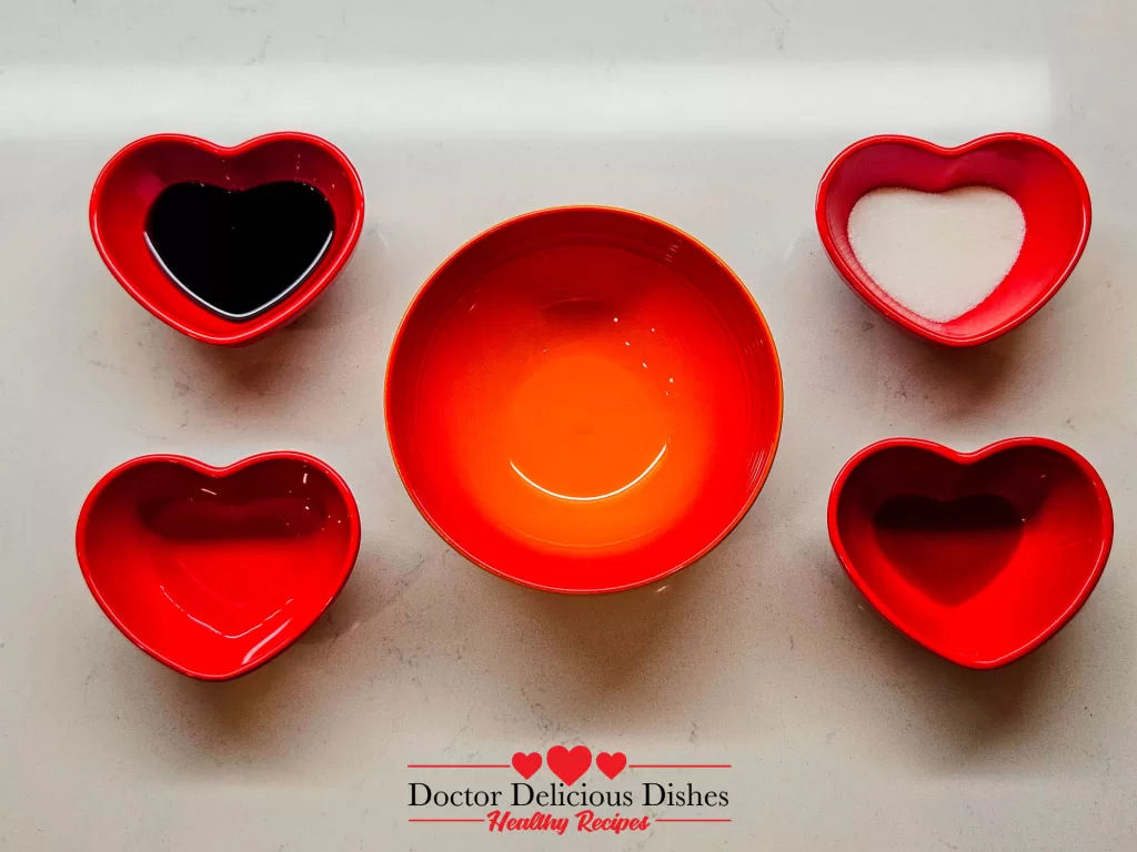 Soy sauce, sugar, mirin, and sake displayed in red heart bowls for Chicken Soboro Don sauce preparation by Doctor Delicious Dishes.