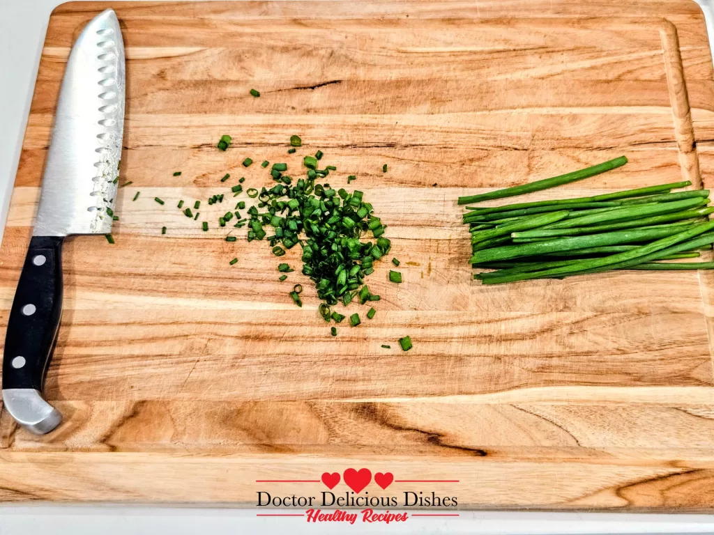 Fresh green onions being chopped for Tofu with Oyster Sauce on a wooden cutting board. Fresh green onions being chopped for Tofu with Oyster Sauce on a wooden cutting board.