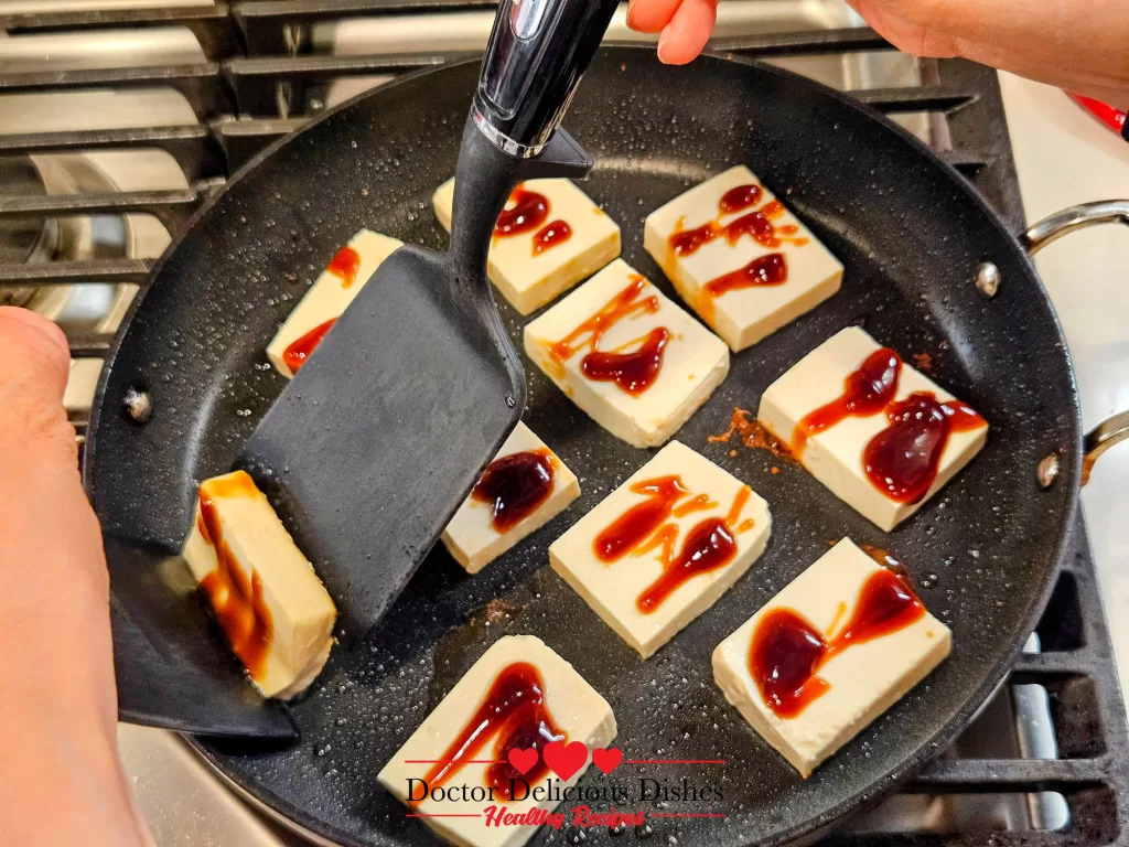 Using a spatula to gently flip tofu while cooking Tofu with Oyster Sauce.