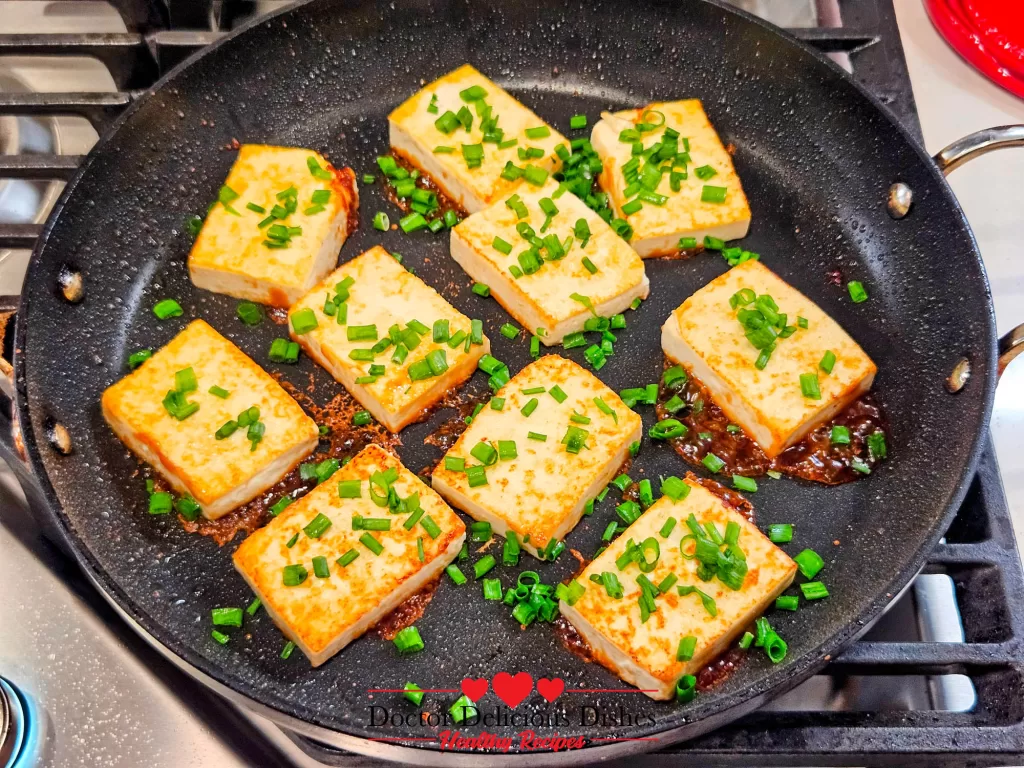 Adding fresh chopped green onions on top of tofu cooked with oyster sauce.