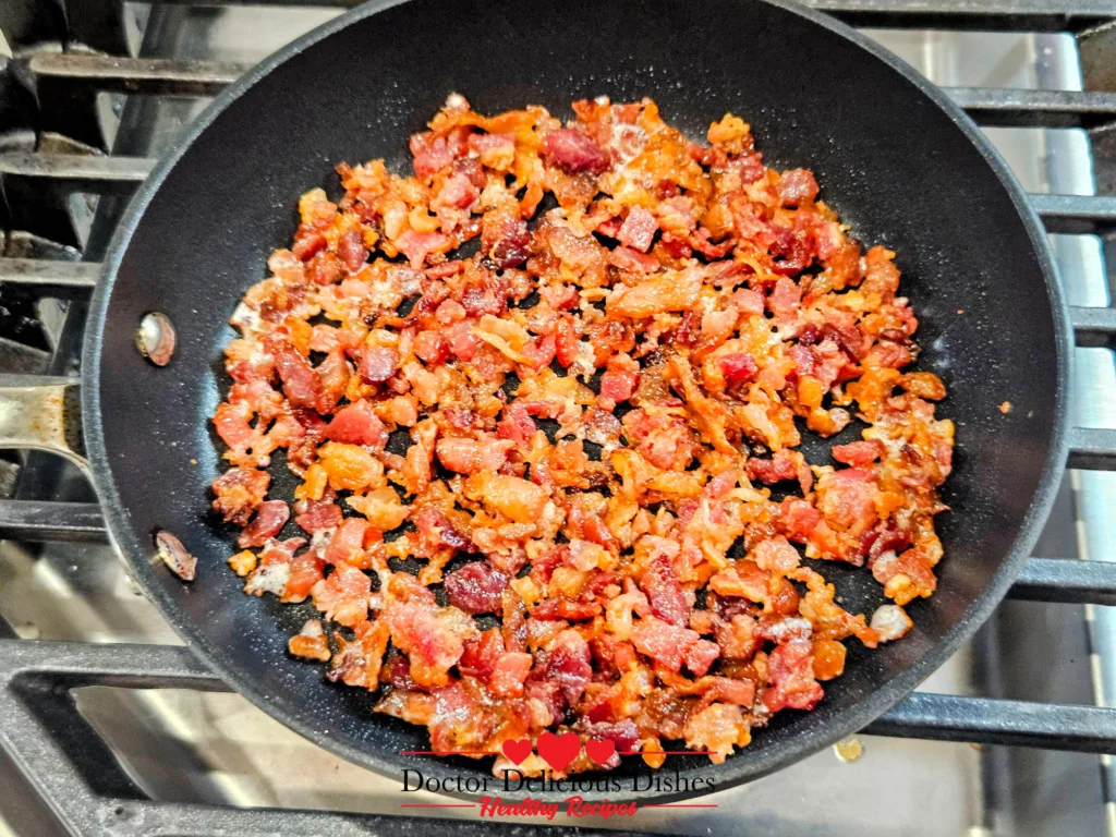 Crispy bacon bits cooking in a skillet to top an air fryer baked potato