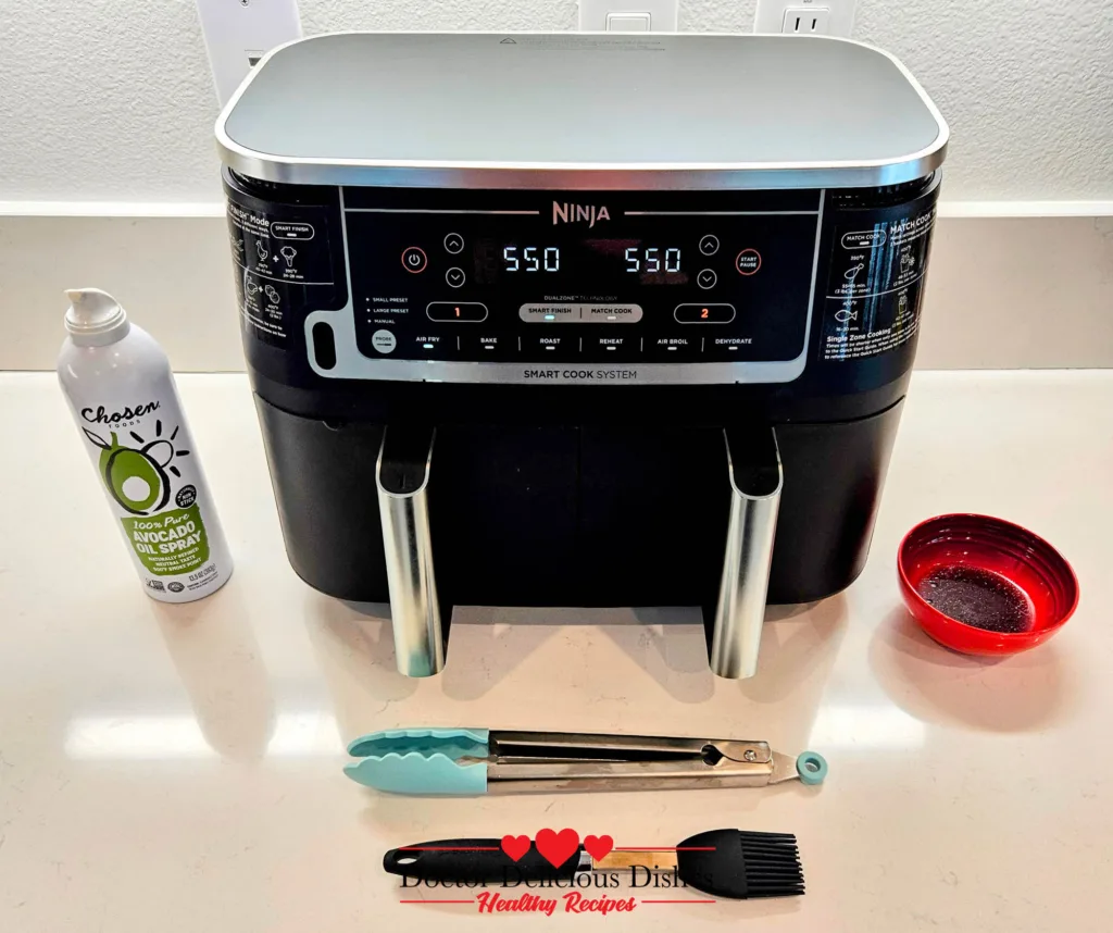 Air fryer tools, glaze bowl, and avocado oil spray set up for cooking air fryer chicken katsu and corn.