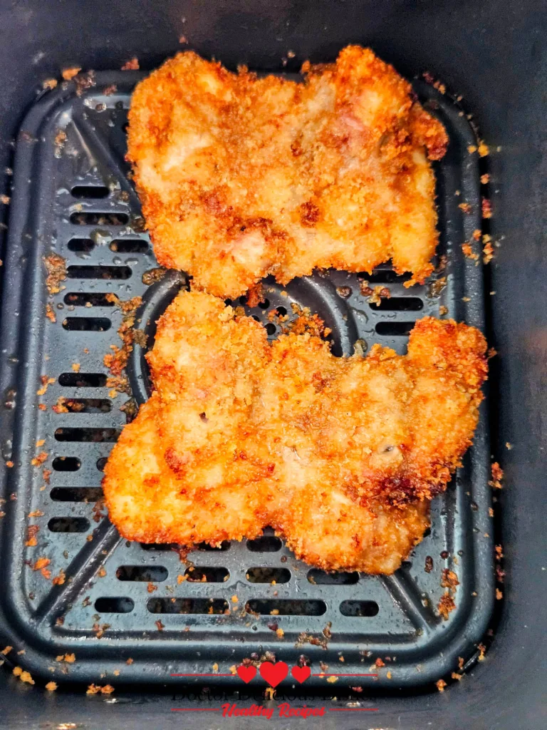 Crispy air fryer chicken katsu just finished cooking in the basket with a golden panko crust.