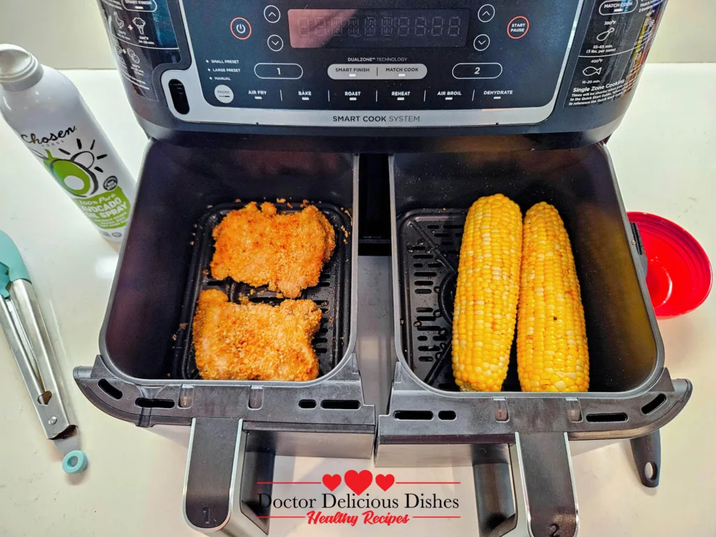 Air fryer corn on the cob cooking alongside chicken katsu in dual baskets