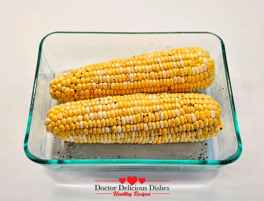 Air fryer corn on the cob seasoned with salt and pepper in a glass dish