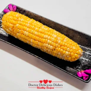 Air Fryer Corn on the Cob Yaki-Tōmorokoshi plated on a black dish with pink petals for garnish