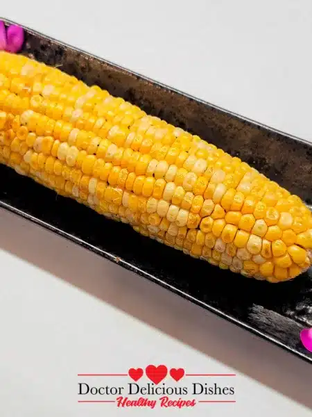 Air Fryer Corn on the Cob Yaki-Tōmorokoshi plated on a black dish with pink petals for garnish