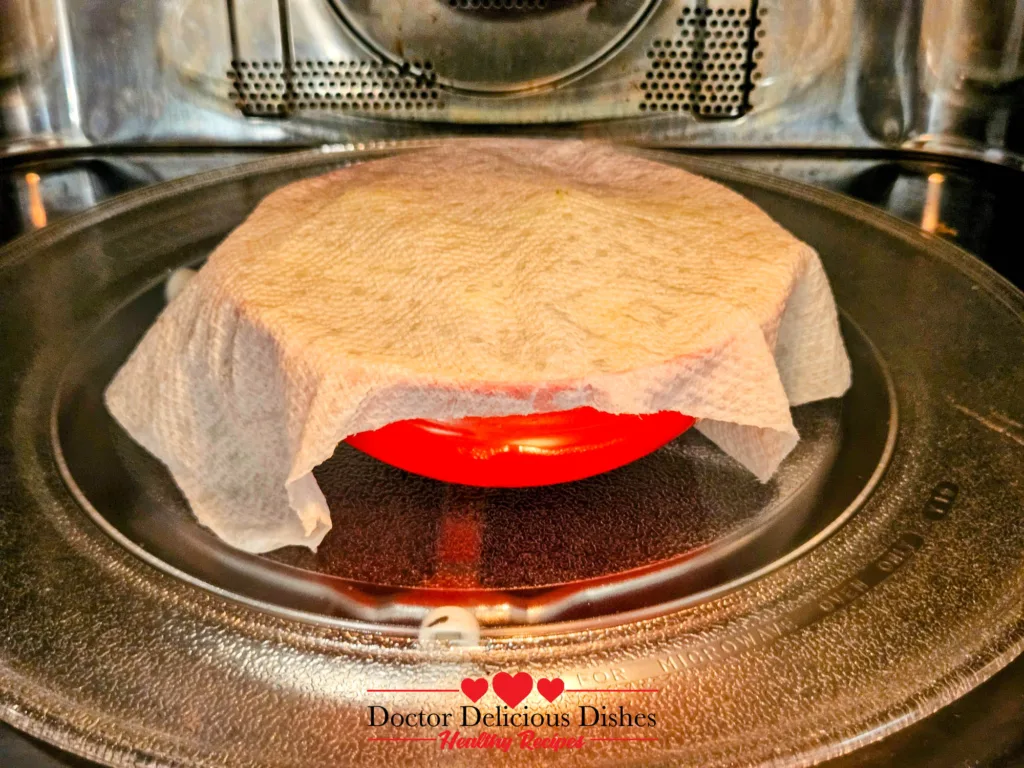 Frozen broccoli covered with a paper towel for steaming in the microwave