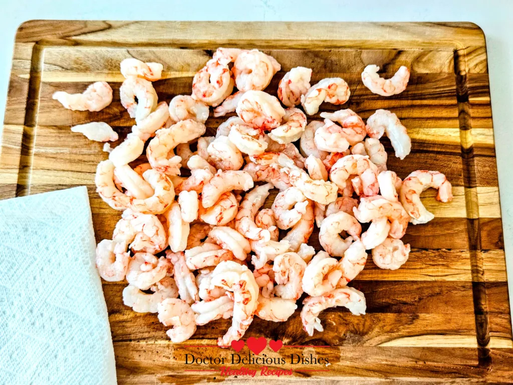 Garlic Butter Shrimp step showing raw shrimp patted dry on a cutting board for better browning.