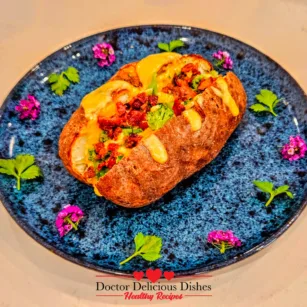 Loaded air fryer baked potato topped with nacho cheese sauce broccoli and bacon bits on a blue plate