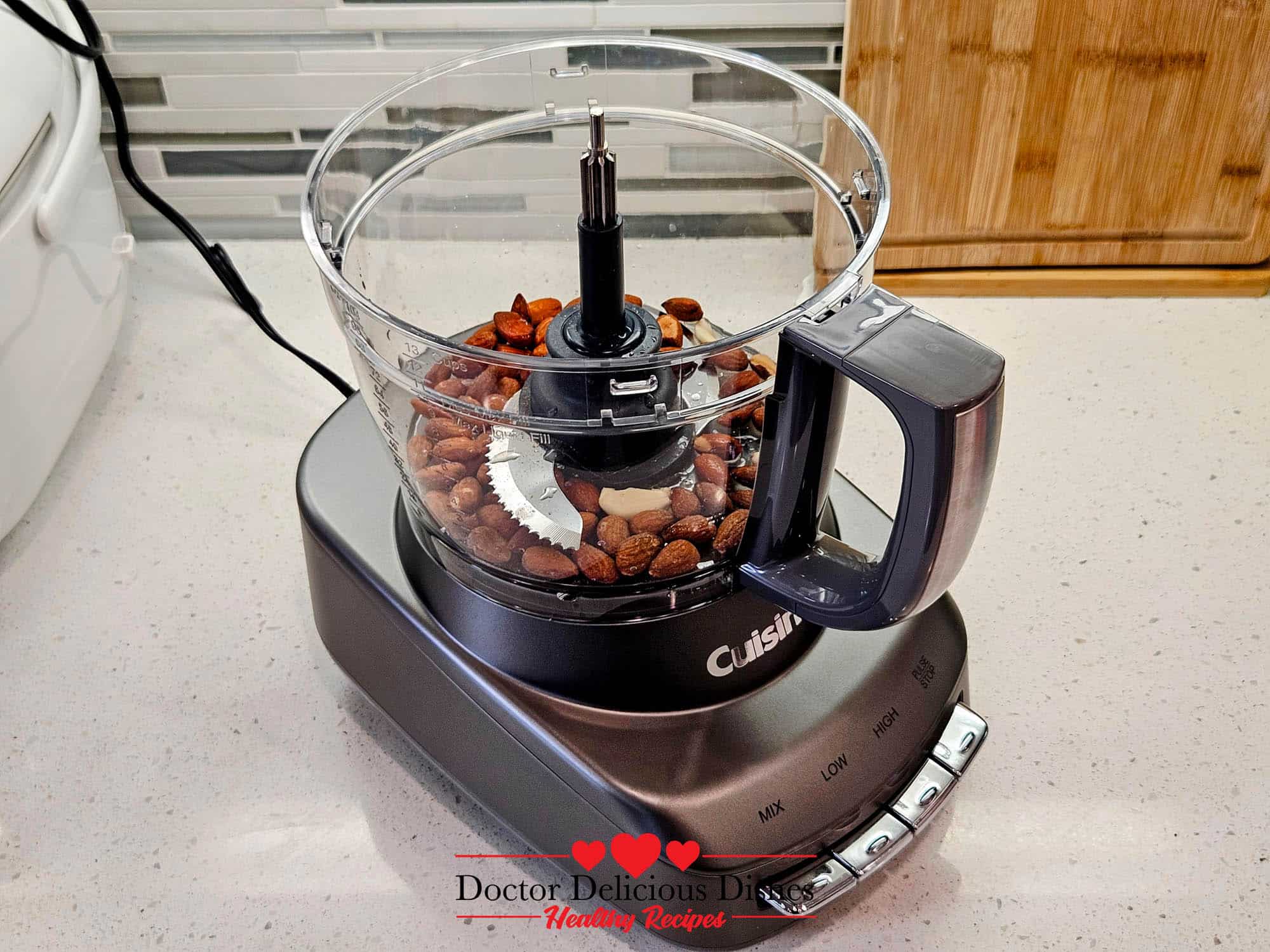 Almonds and garlic in a Cuisinart food processor, ready to be blended into homemade almond pesto.