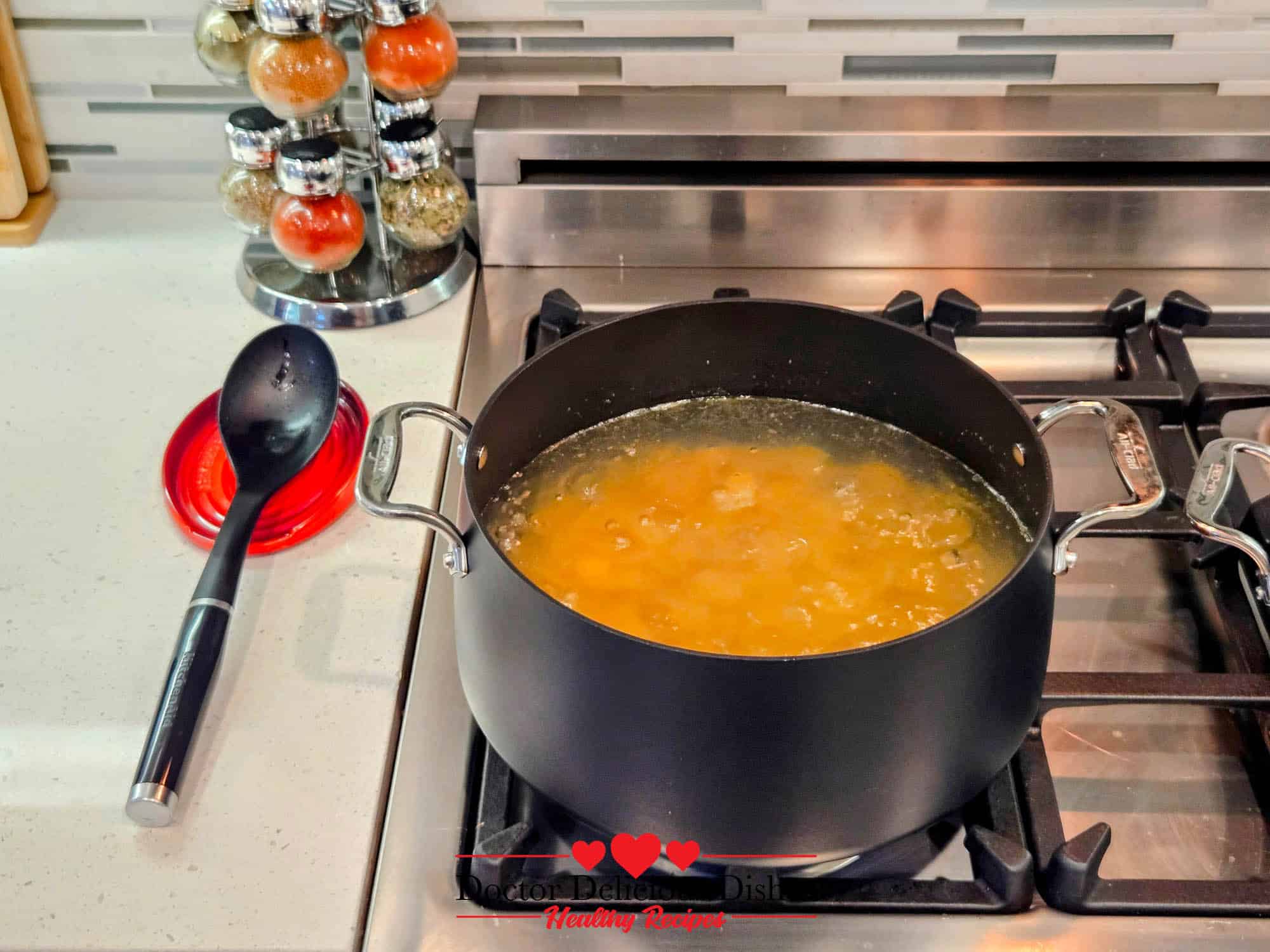 Large shell pasta boiling in a pot on the stove for Almond Pesto Shrimp Pasta.
