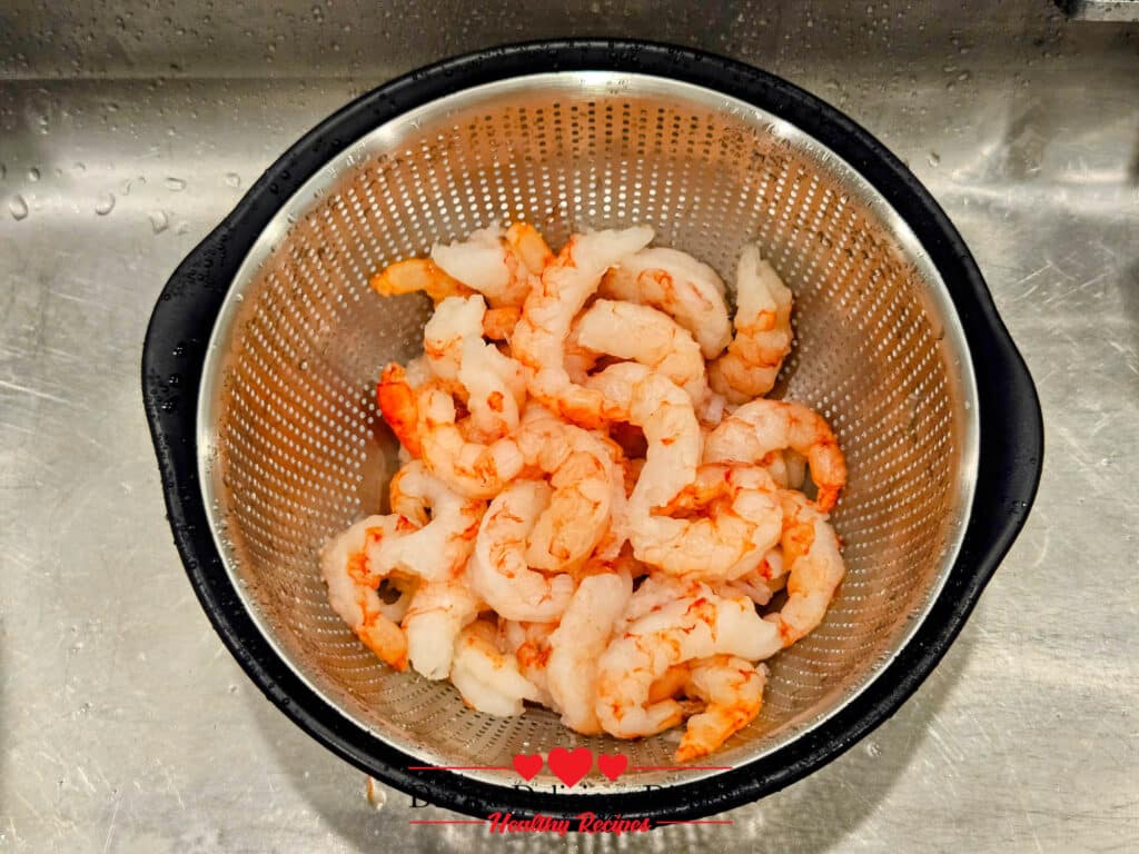 Peeled and deveined shrimp rinsed and drained in a colander before cooking for Almond Pesto Shrimp Pasta.