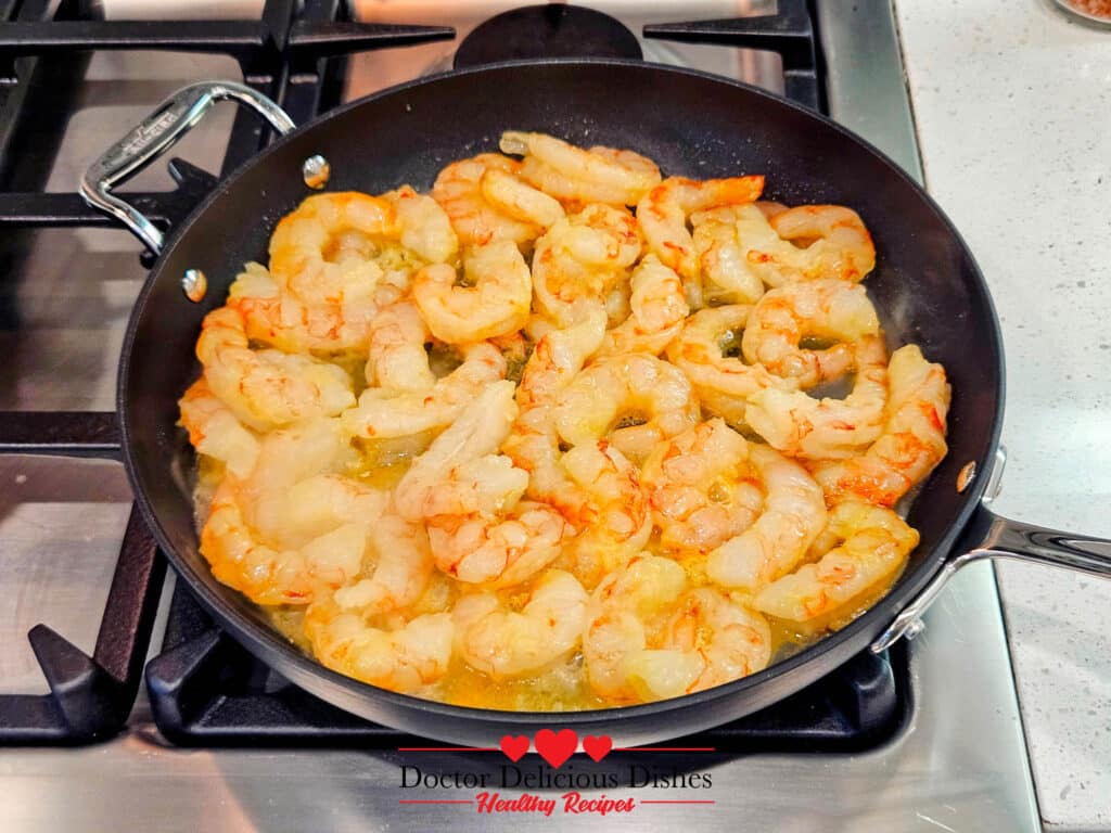 Shrimp cooking in olive oil in a skillet until pink and tender for Almond Pesto Shrimp Pasta.